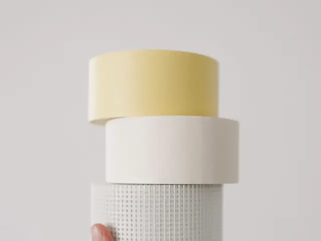 Hand holding stacked rolls of masking tape